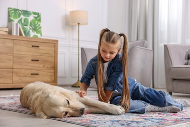 Photo of Girl with her cute Golden Retriever dog on rug at home