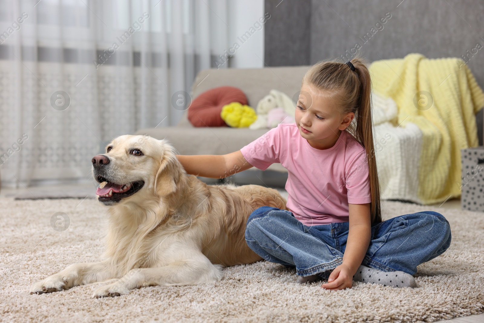 Photo of Girl with her cute Golden Retriever dog on rug at home