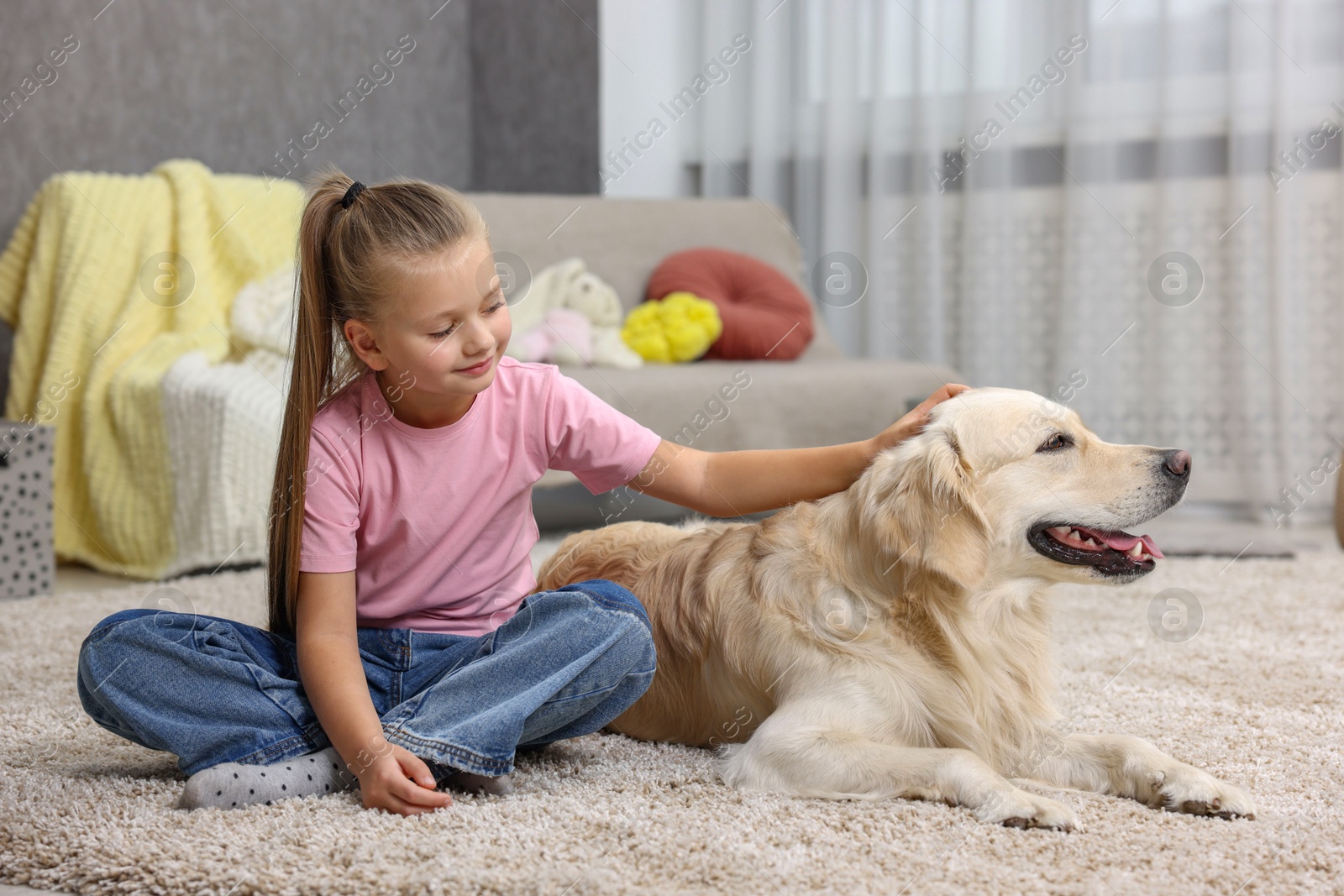 Photo of Girl with her cute Golden Retriever dog on rug at home