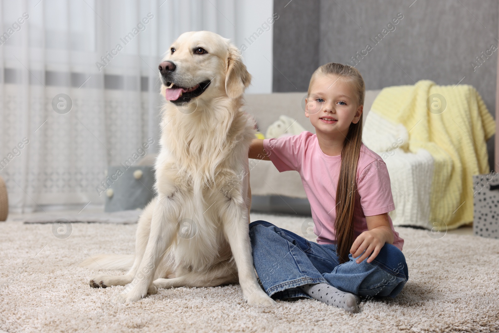 Photo of Girl with her cute Golden Retriever dog on rug at home