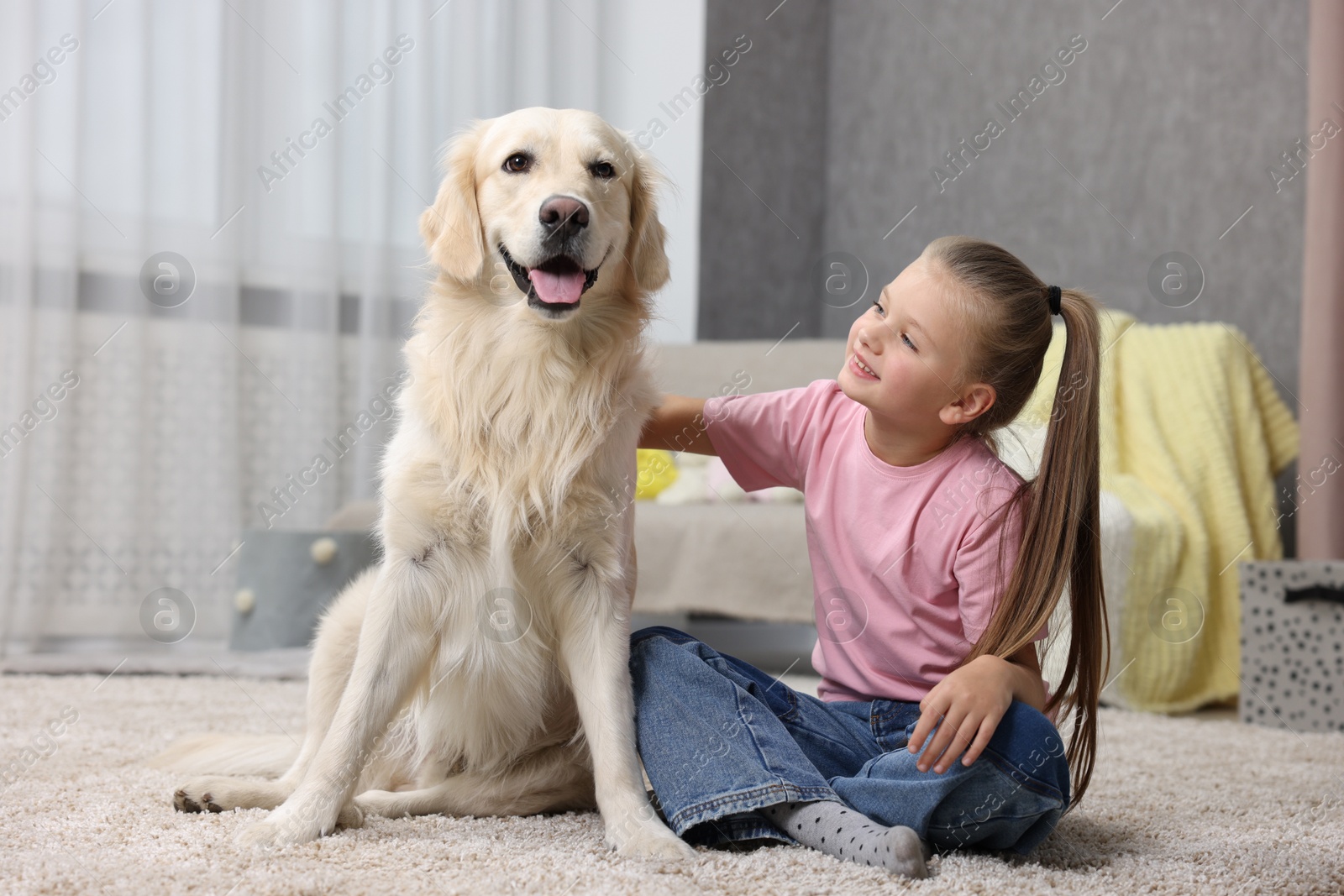 Photo of Girl with her cute Golden Retriever dog on rug at home