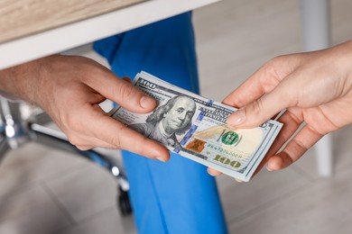 Photo of Corruption concept. Woman giving dollar banknotes to man under table, closeup