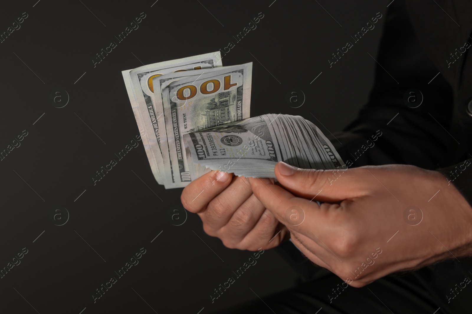 Photo of Corruption concept. Man holding dollar banknotes on black background, closeup