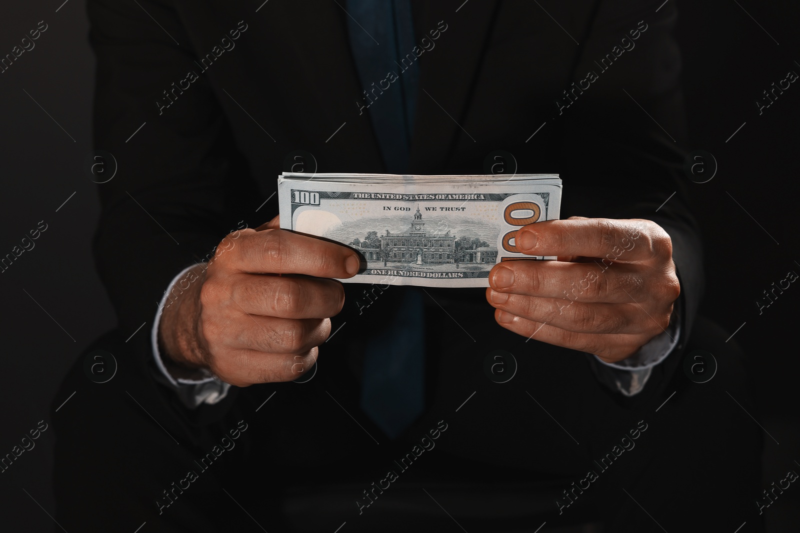 Photo of Corruption concept. Man holding dollar banknotes on black background, closeup