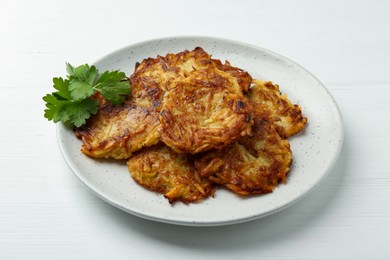 Photo of Delicious potato pancakes and parsley on white wooden table, closeup