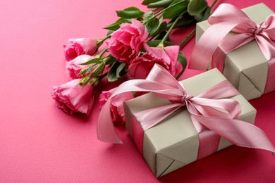 Photo of Beautiful gift boxes with bows and eustoma flowers on pink background