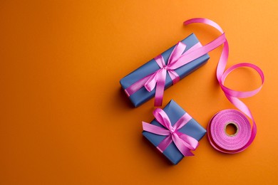 Photo of Beautiful gift boxes with pink bows and ribbon on orange background, top view. Space for text