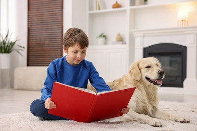 Photo of Boy reading book with his cute dog at home