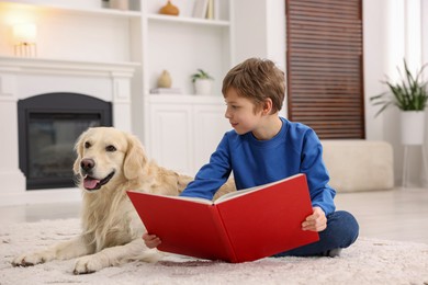 Photo of Boy reading book with his cute dog at home