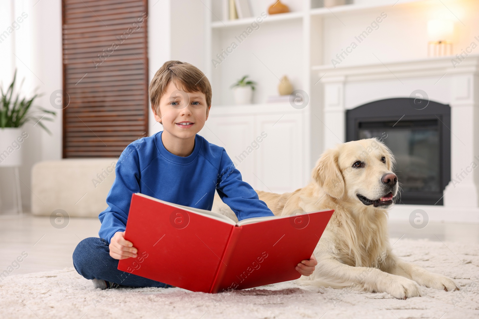 Photo of Boy reading book with his cute dog at home