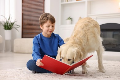 Photo of Boy reading book with his cute dog at home