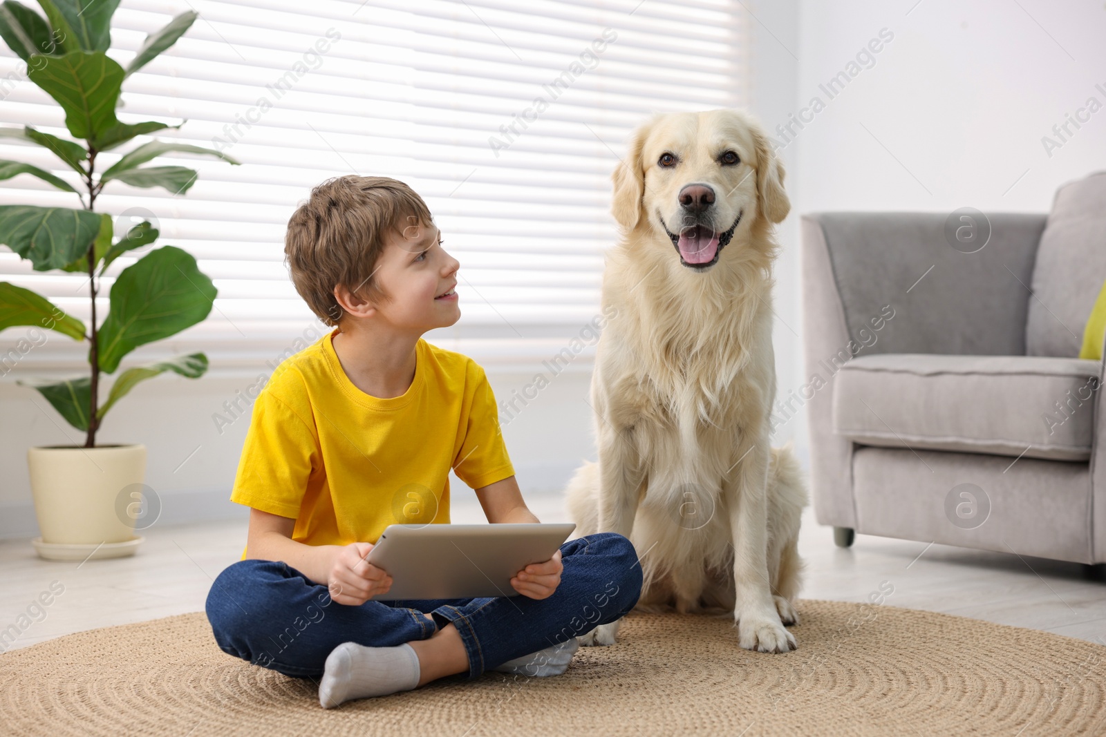 Photo of Boy using tablet with his cute dog at home