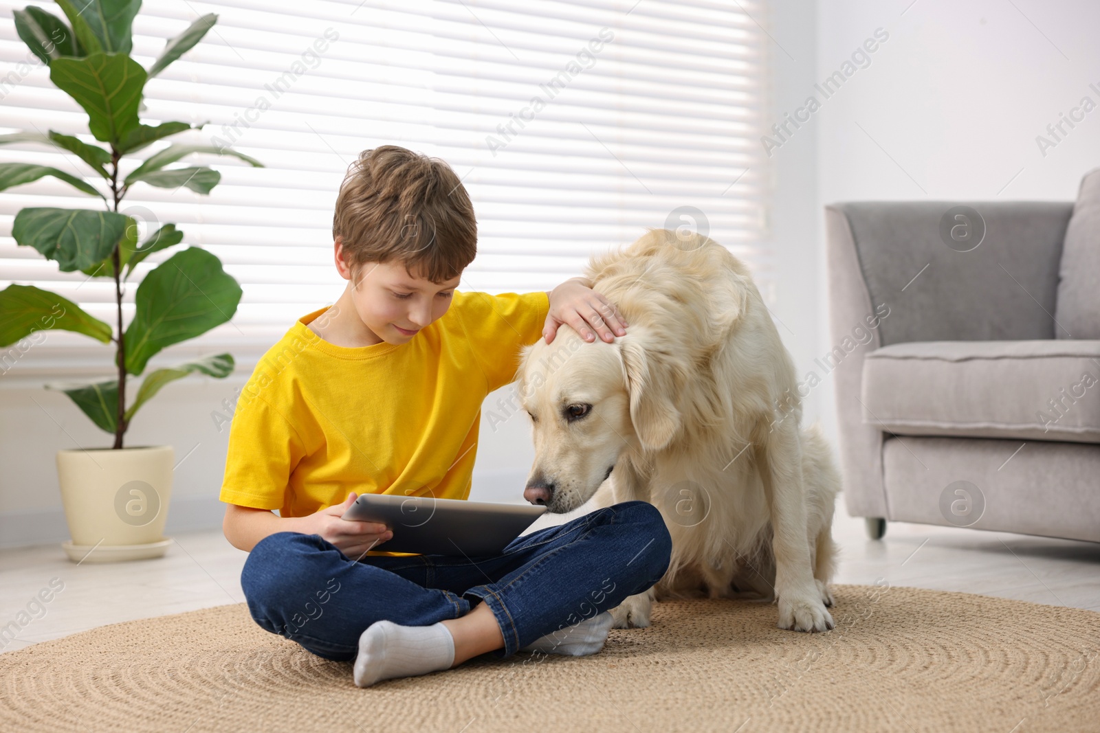 Photo of Boy using tablet with his cute dog at home