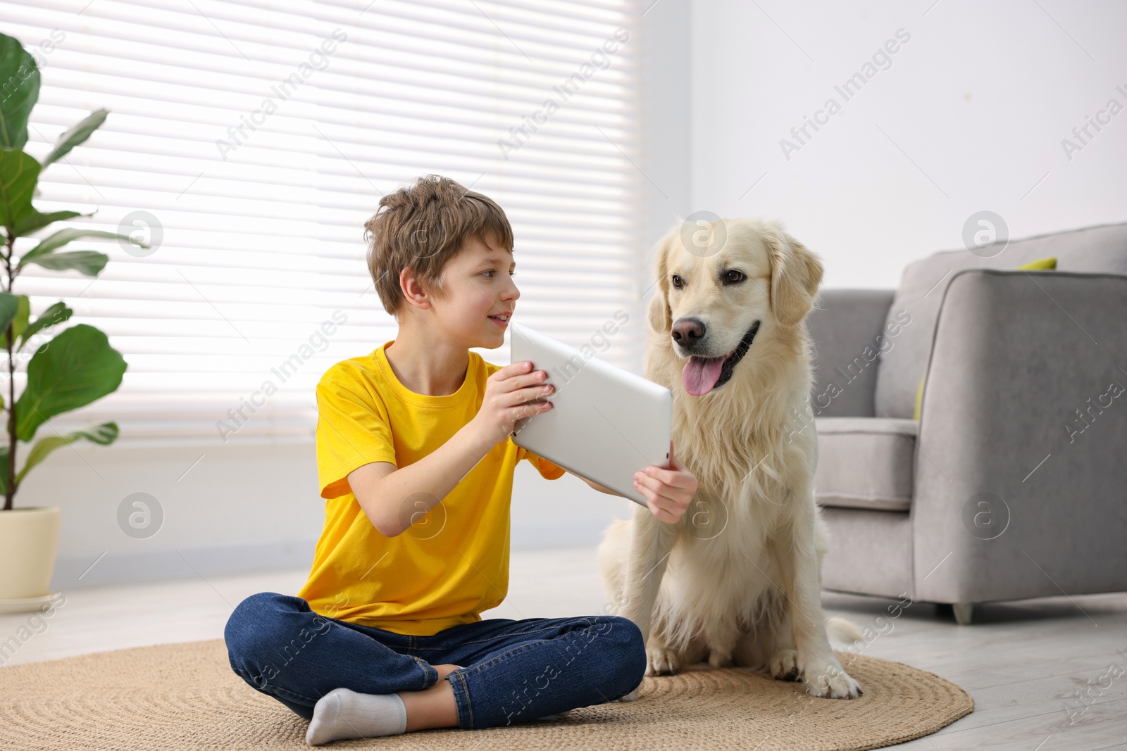 Photo of Boy showing tablet to his cute dog at home