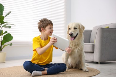 Photo of Boy showing tablet to his cute dog at home