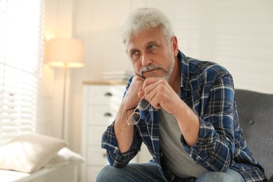 Photo of Lonely senior man sitting in armchair at home. Space for text