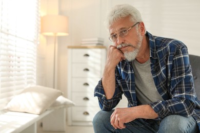 Photo of Lonely senior man sitting in armchair at home. Space for text