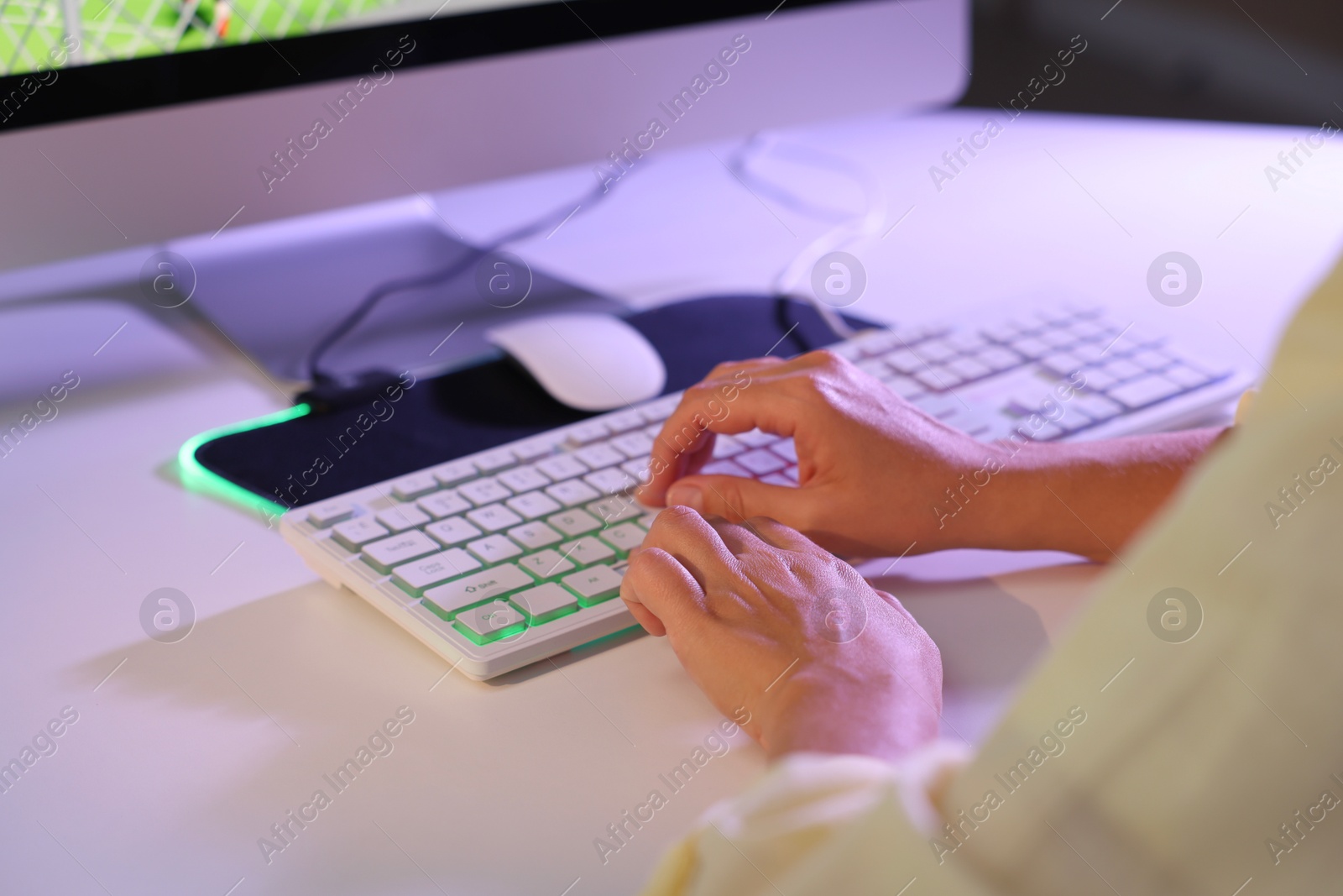 Photo of Woman using computer keyboard at white table indoors, closeup