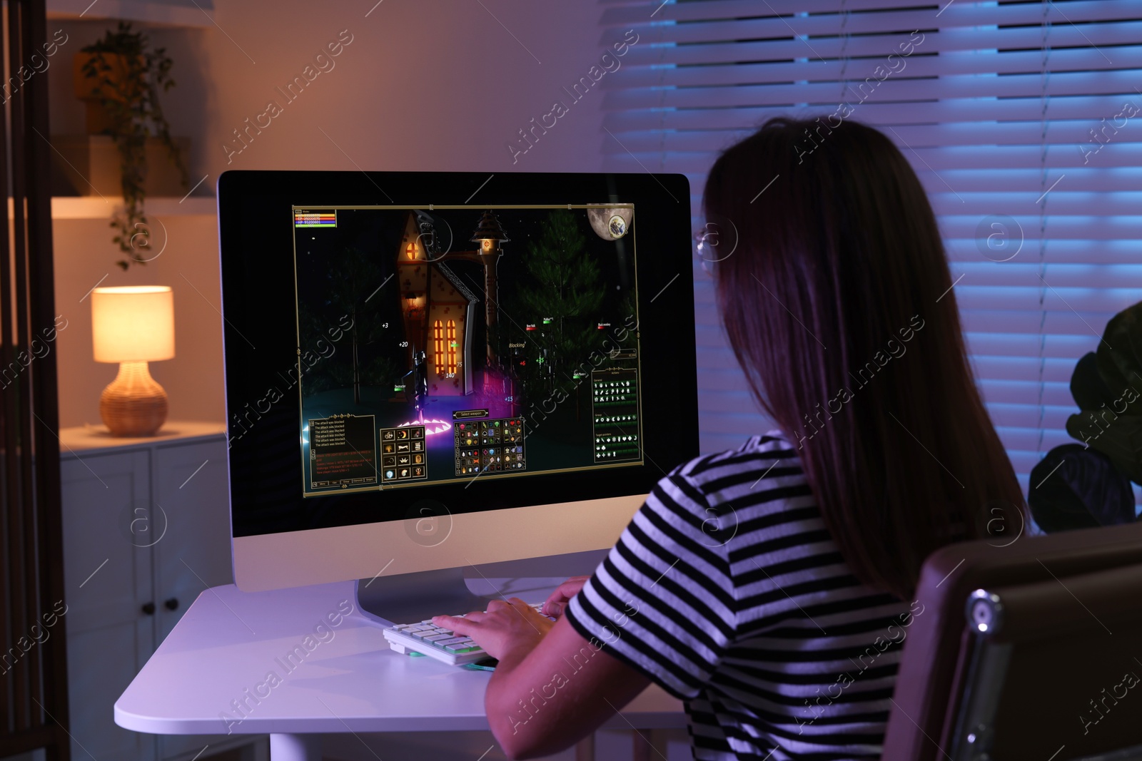 Photo of Woman playing video game with keyboard at table indoors, back view