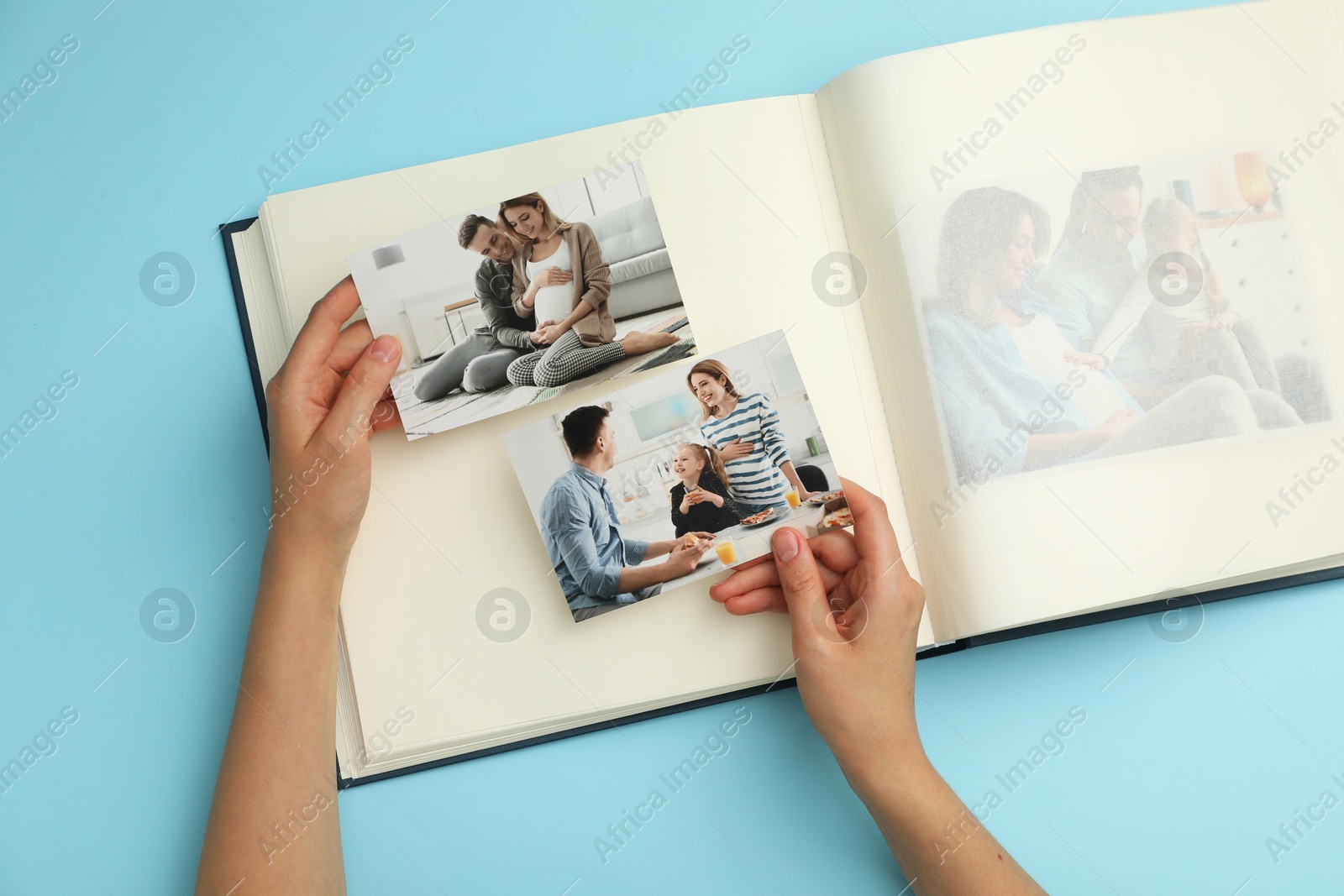 Photo of Woman with open photo album and different photos on light blue background, top view