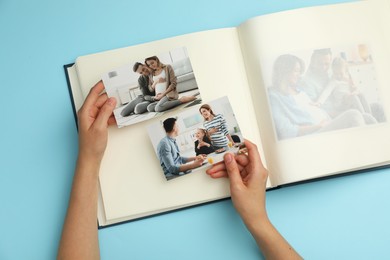 Photo of Woman with open photo album and different photos on light blue background, top view