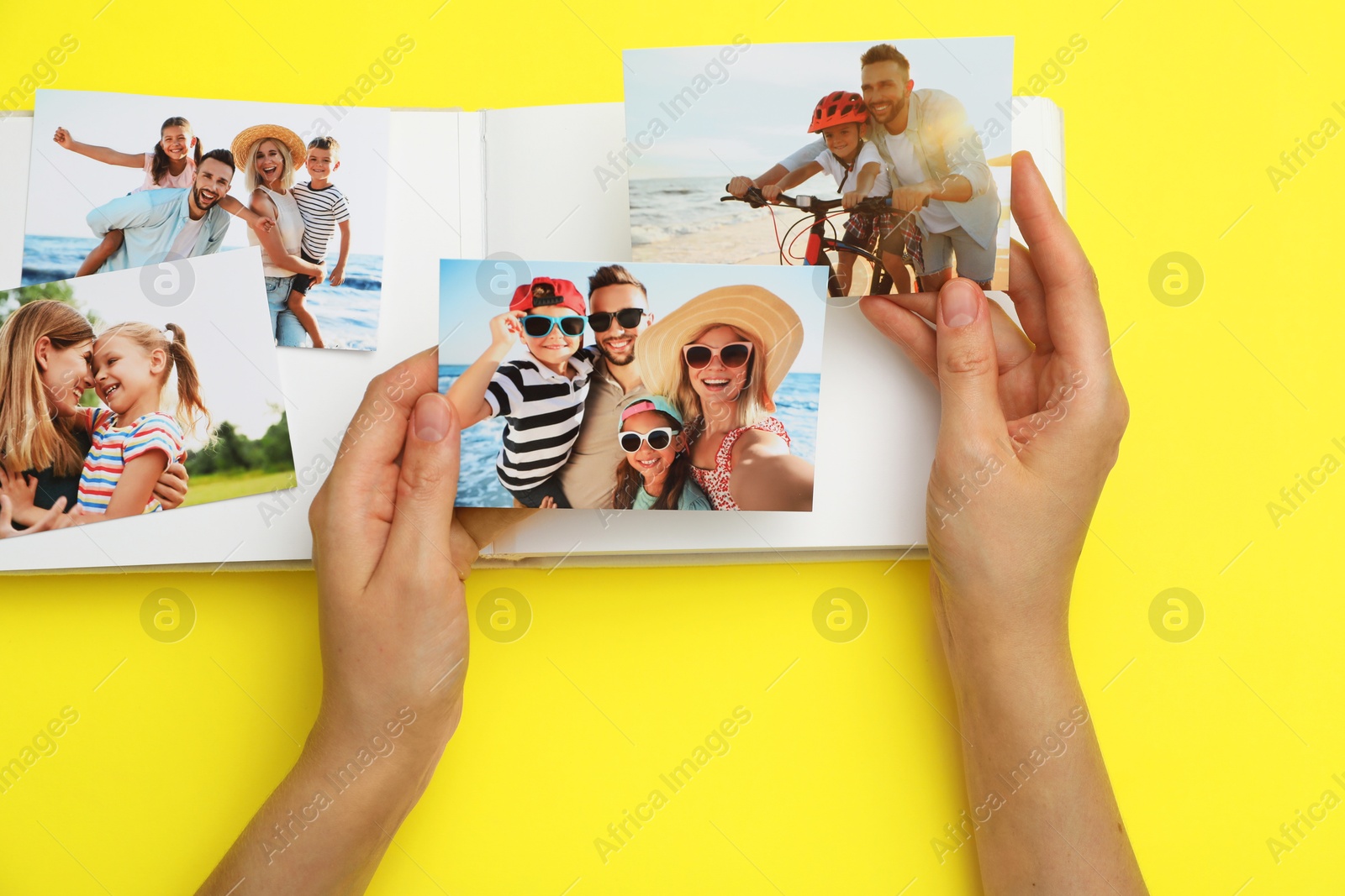 Photo of Woman with open photo album and different photos on yellow background, top view