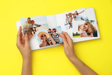 Photo of Woman with open photo album and different photos on yellow background, top view