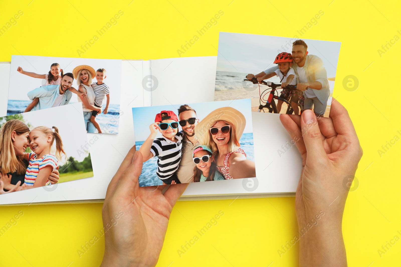 Photo of Woman with open photo album and different photos on yellow background, top view