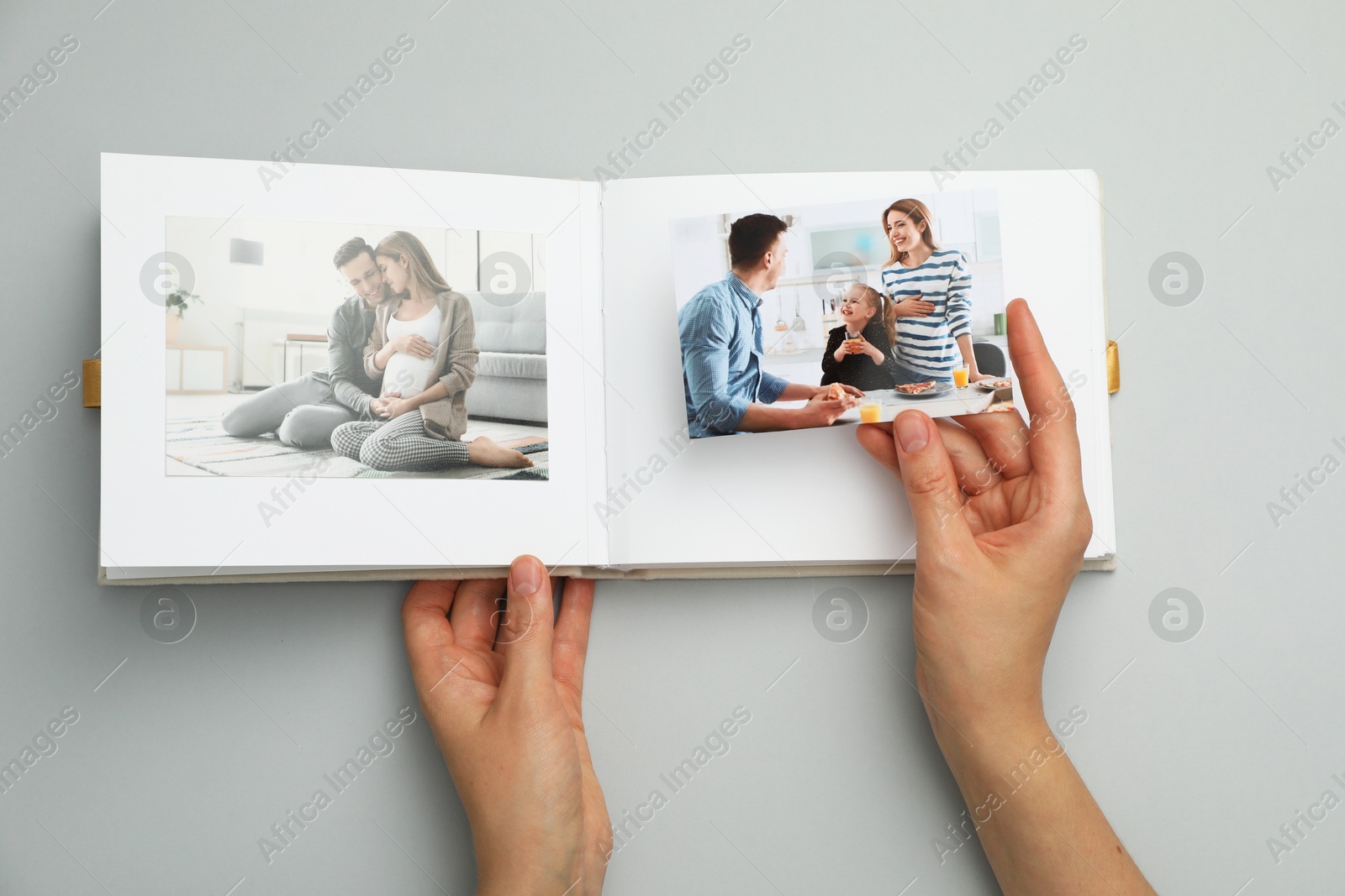 Photo of Woman with open photo album and photos on grey background, top view