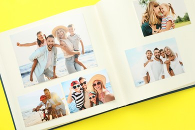 Photo of Open photo album with different photos on yellow background, top view