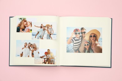 Photo of Open photo album with different photos on pink background, top view