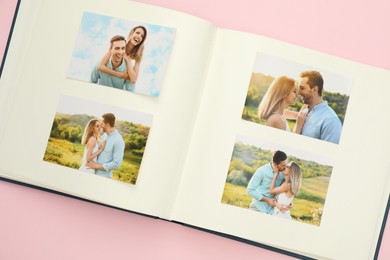 Photo of Open photo album with different photos on pink background, top view