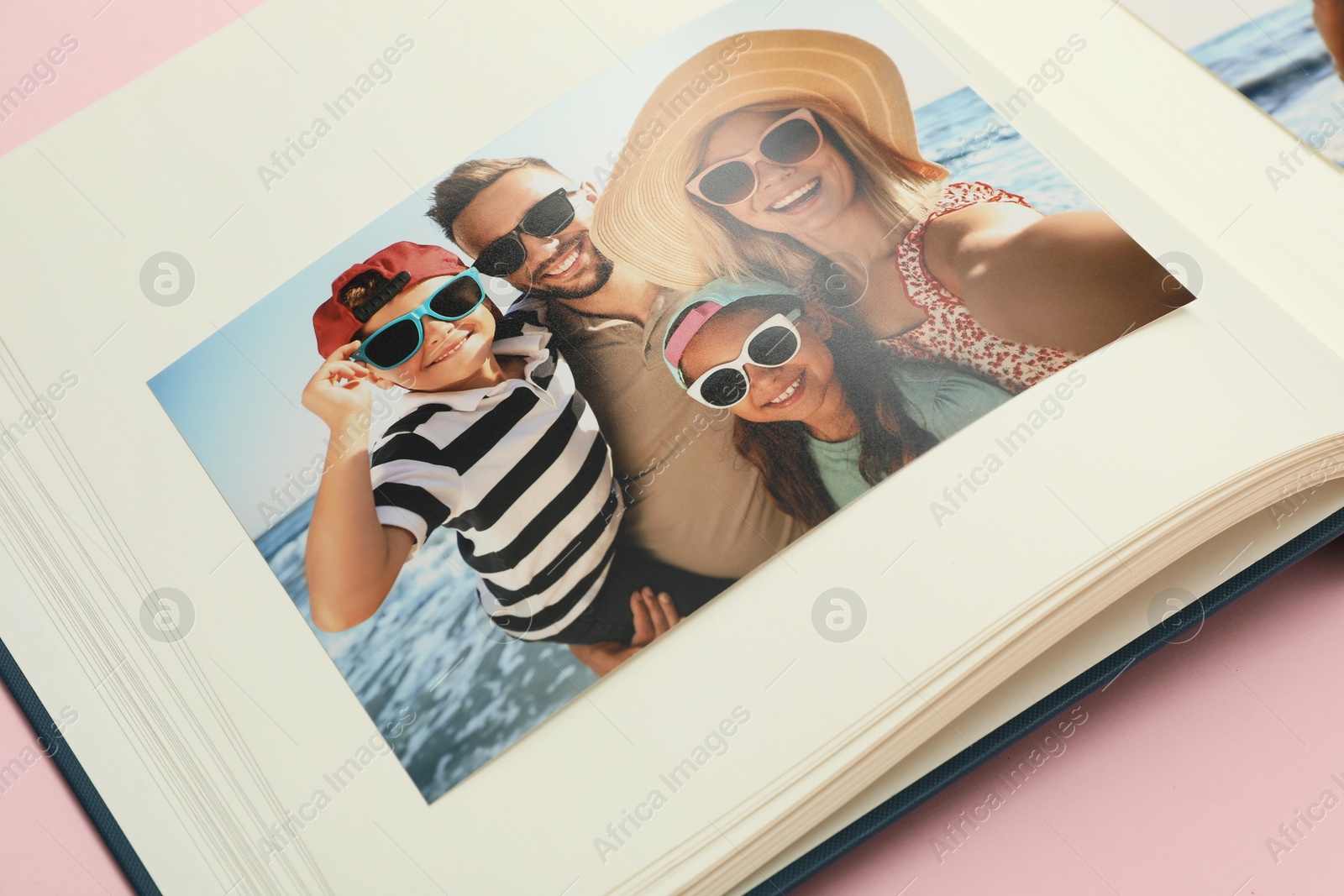 Photo of Open photo album on pink background, closeup