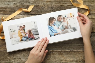 Woman with different photos in open photo album at wooden table, top view