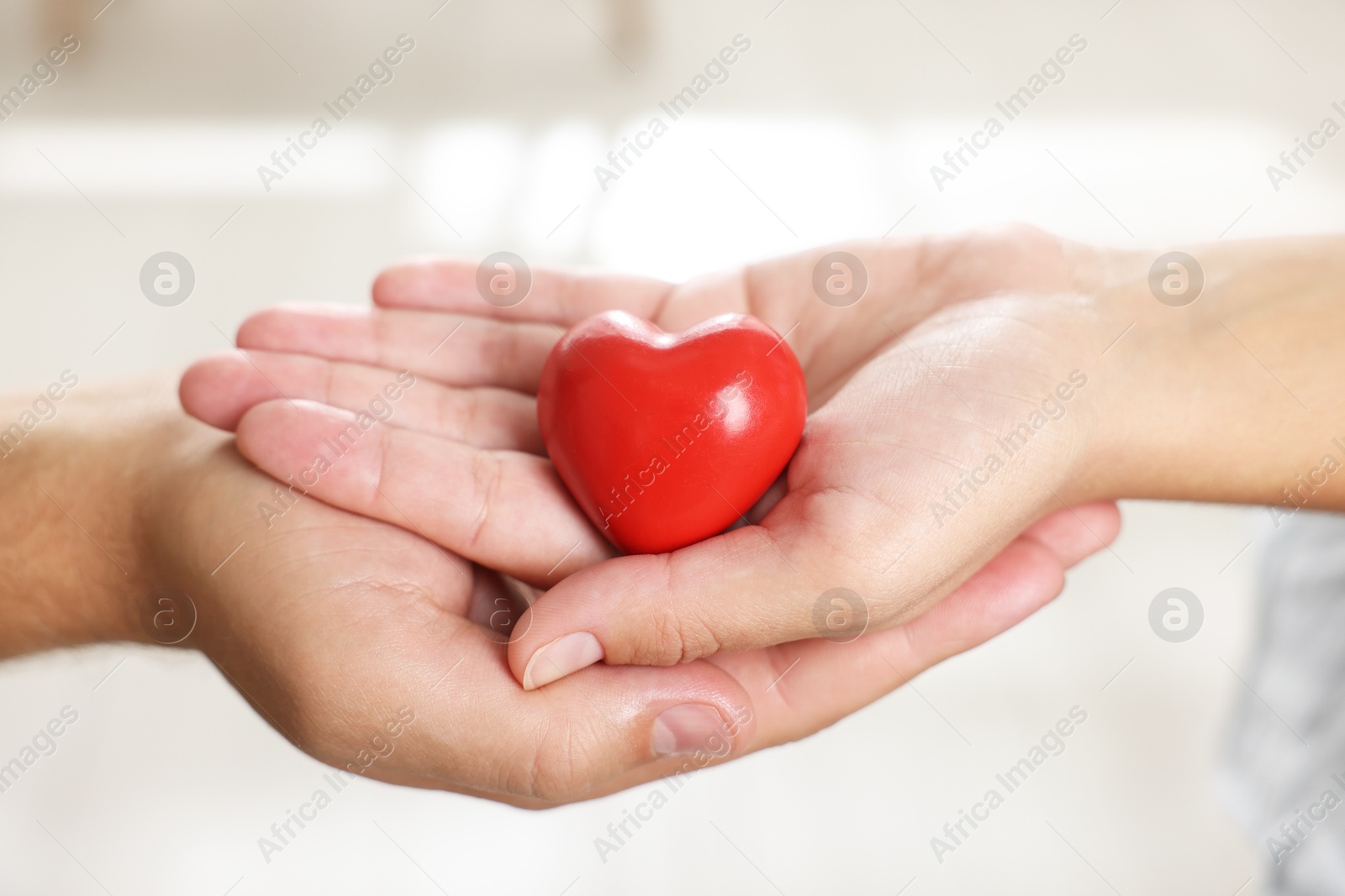 Photo of Little girl and her father with red heart figure indoors, closeup