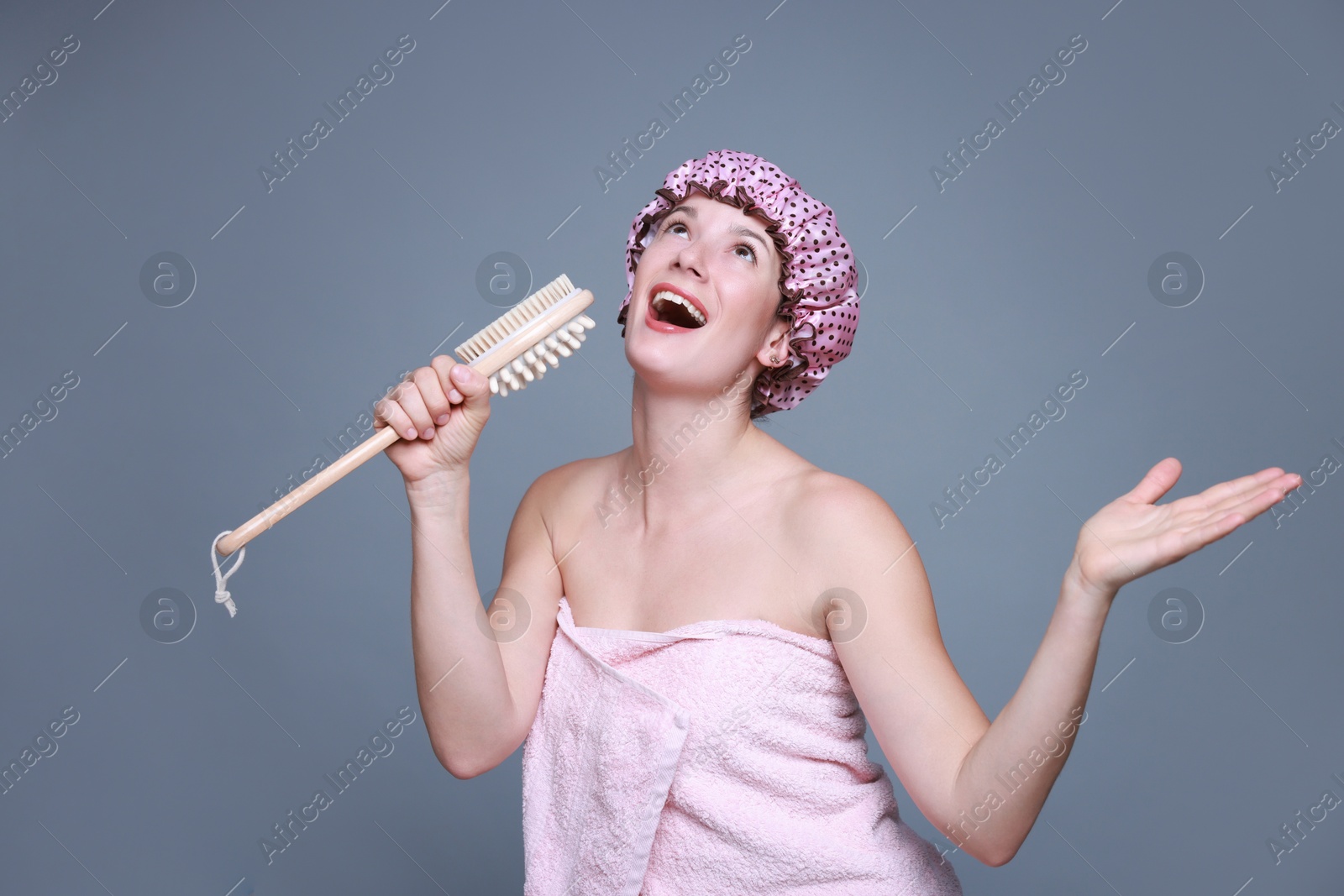 Photo of Woman with shower cap and brush singing on grey background