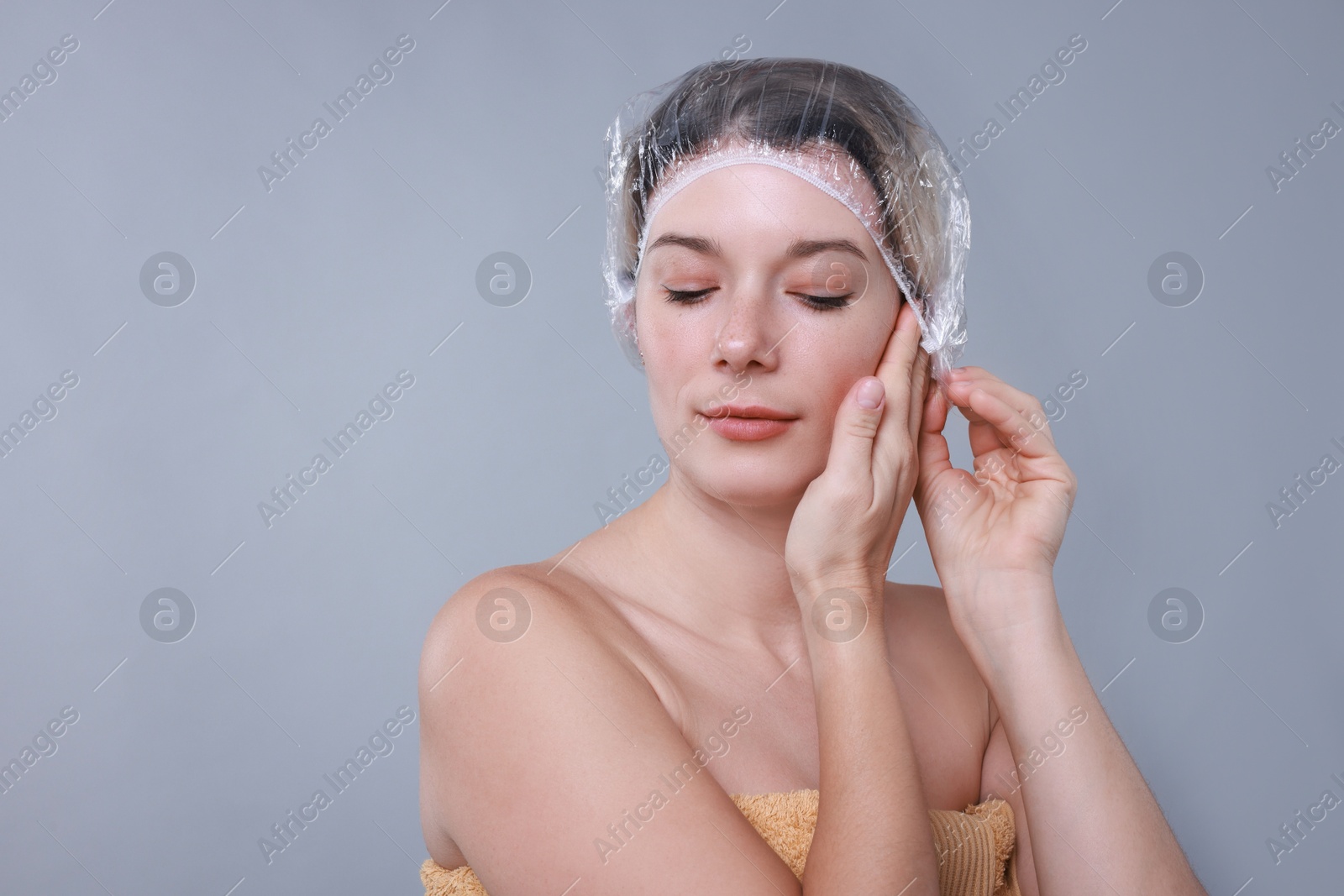 Photo of Woman wearing shower cap on grey background, space for text