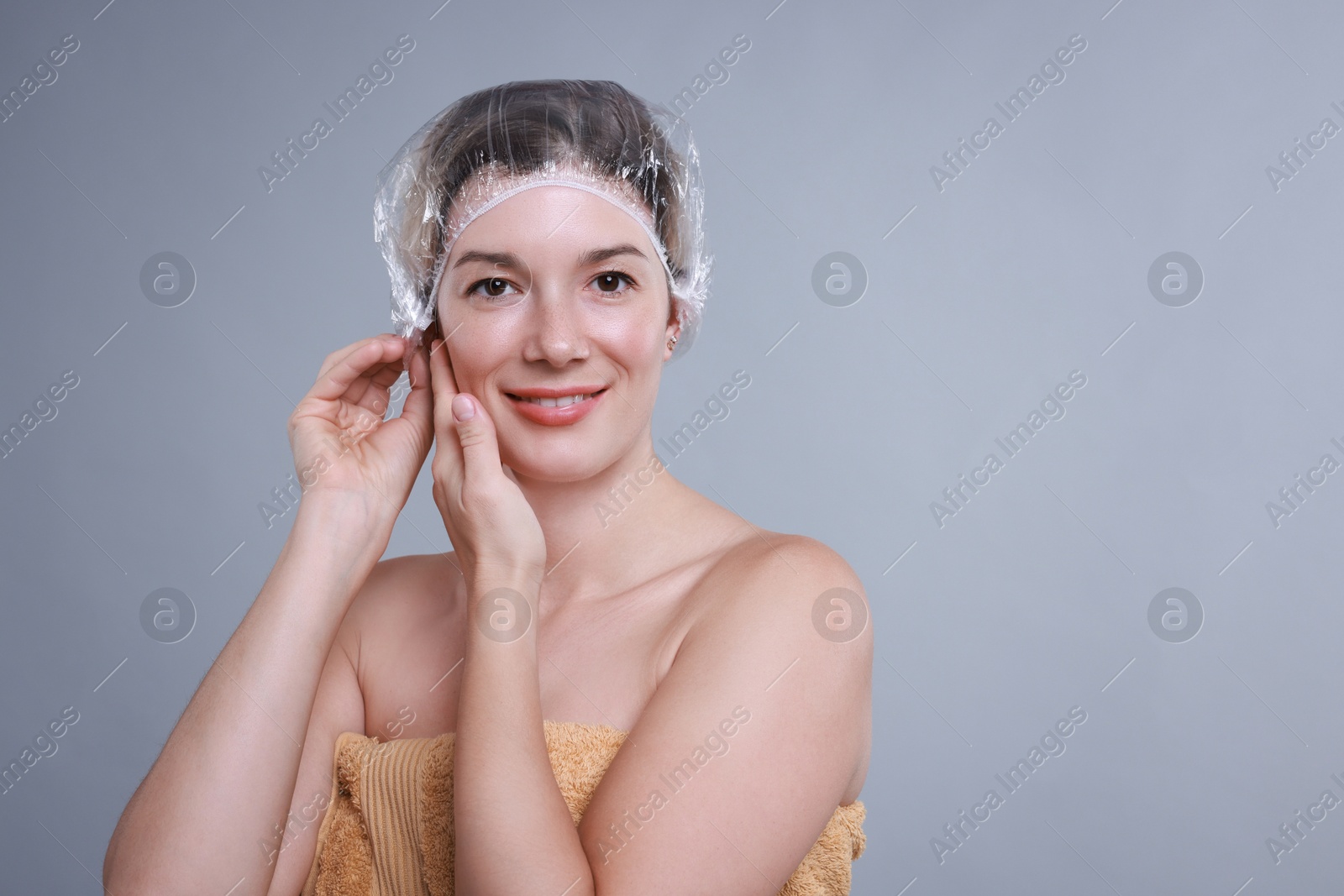 Photo of Woman wearing shower cap on grey background, space for text