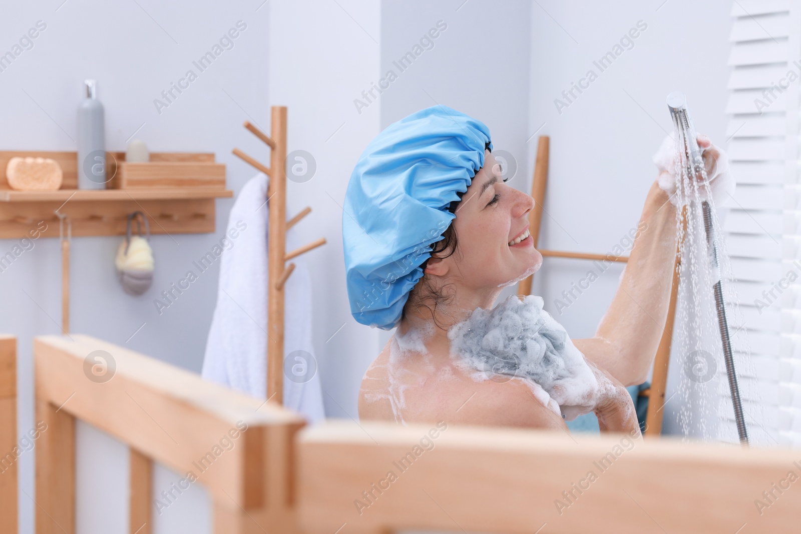 Photo of Woman with cap and mesh sponge taking shower in bathroom