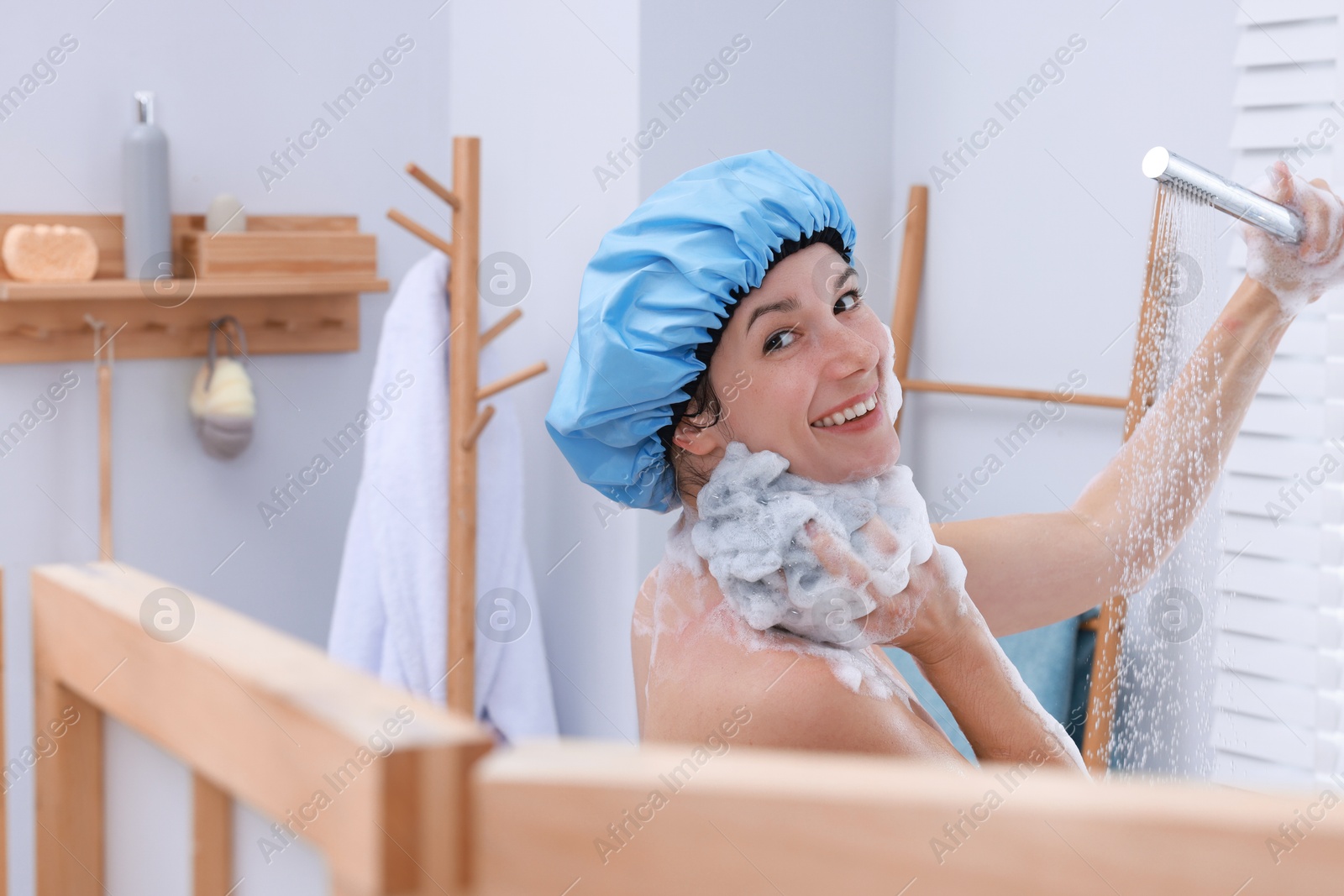 Photo of Woman with cap and mesh sponge taking shower in bathroom