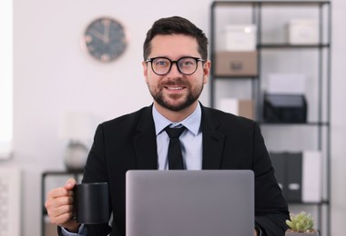 Photo of Banker with cup of drink using laptop in office