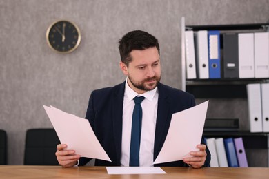 Photo of Banker working with documents at wooden table in office