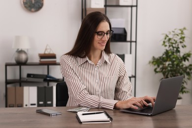 Photo of Banker working with laptop at wooden table in office