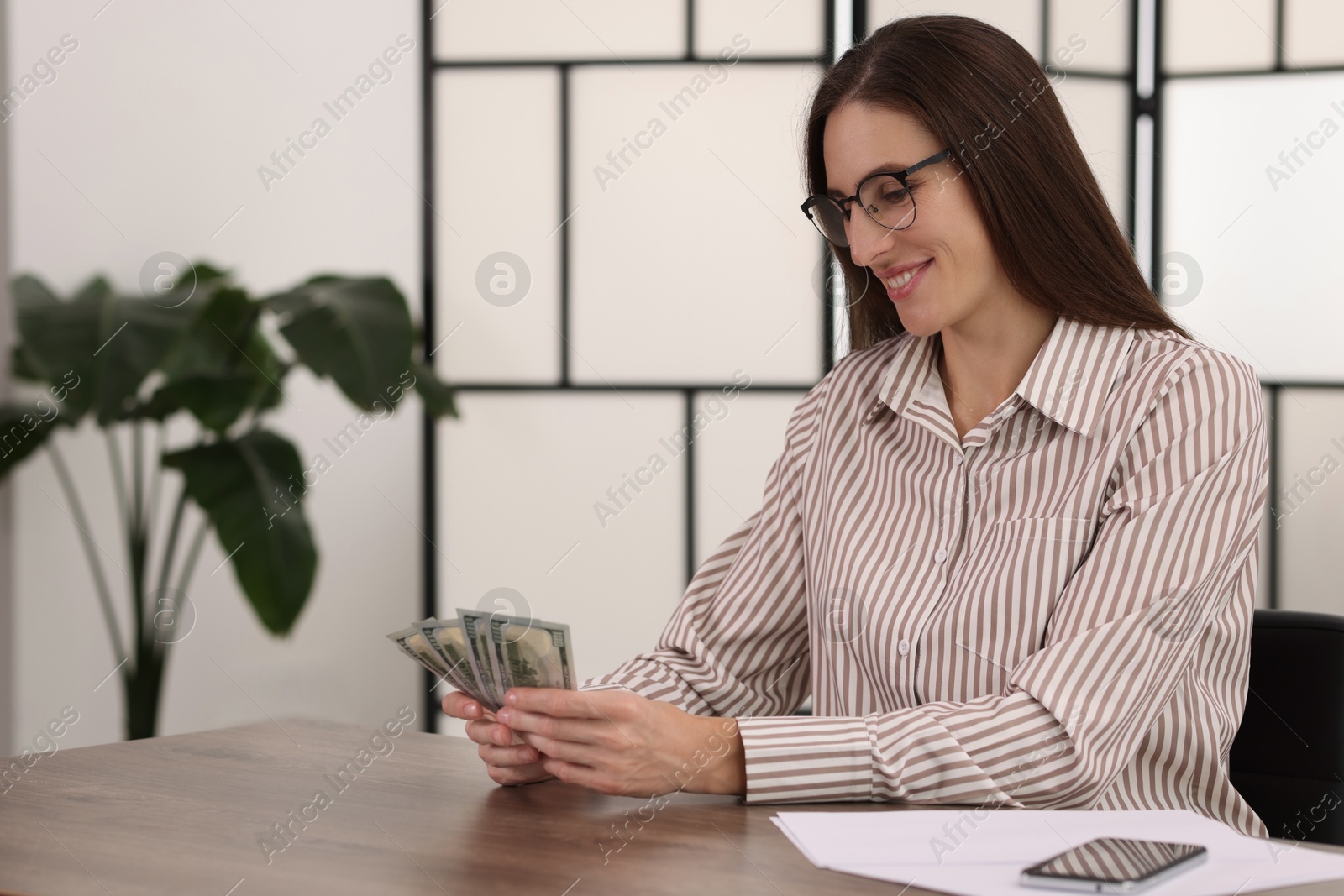 Photo of Banker with dollar banknotes at wooden table in office. Space for text