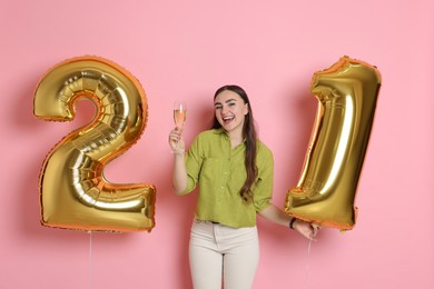 Photo of Coming of age party - 21st birthday. Happy young woman with number shaped balloons on pink background