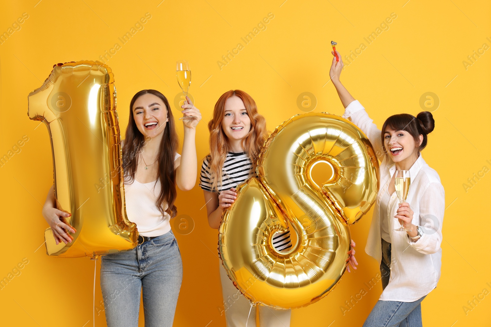 Photo of Coming of age party - 18th birthday. Group of young women celebrating with number shaped balloons on yellow background