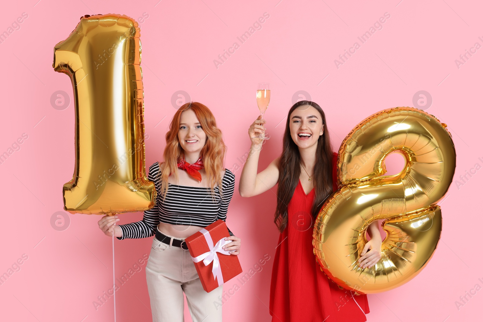 Photo of Coming of age party - 18th birthday. Young women celebrating with number shaped balloons on pink background