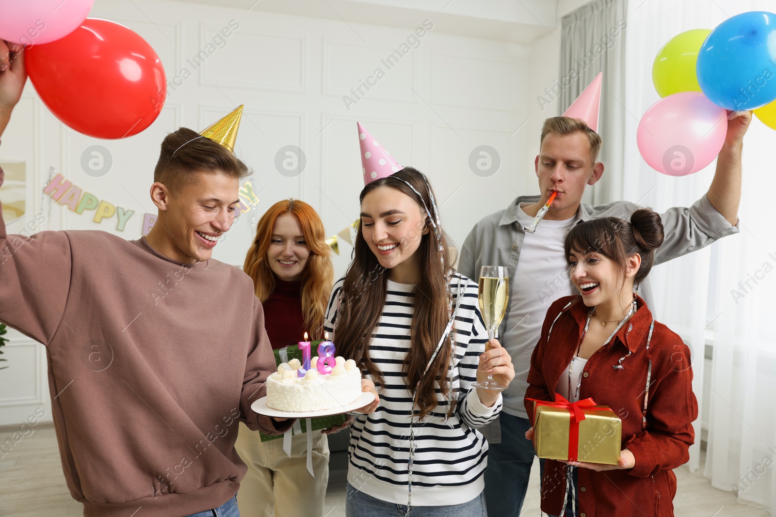 Photo of 18th birthday. Group of friends with tasty cake having coming of age party at home