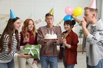 Photo of 18th birthday. Group of friends with tasty cake having coming of age party at home