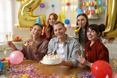 Photo of 21st birthday. Group of happy friends with tasty cake having coming of age party at home